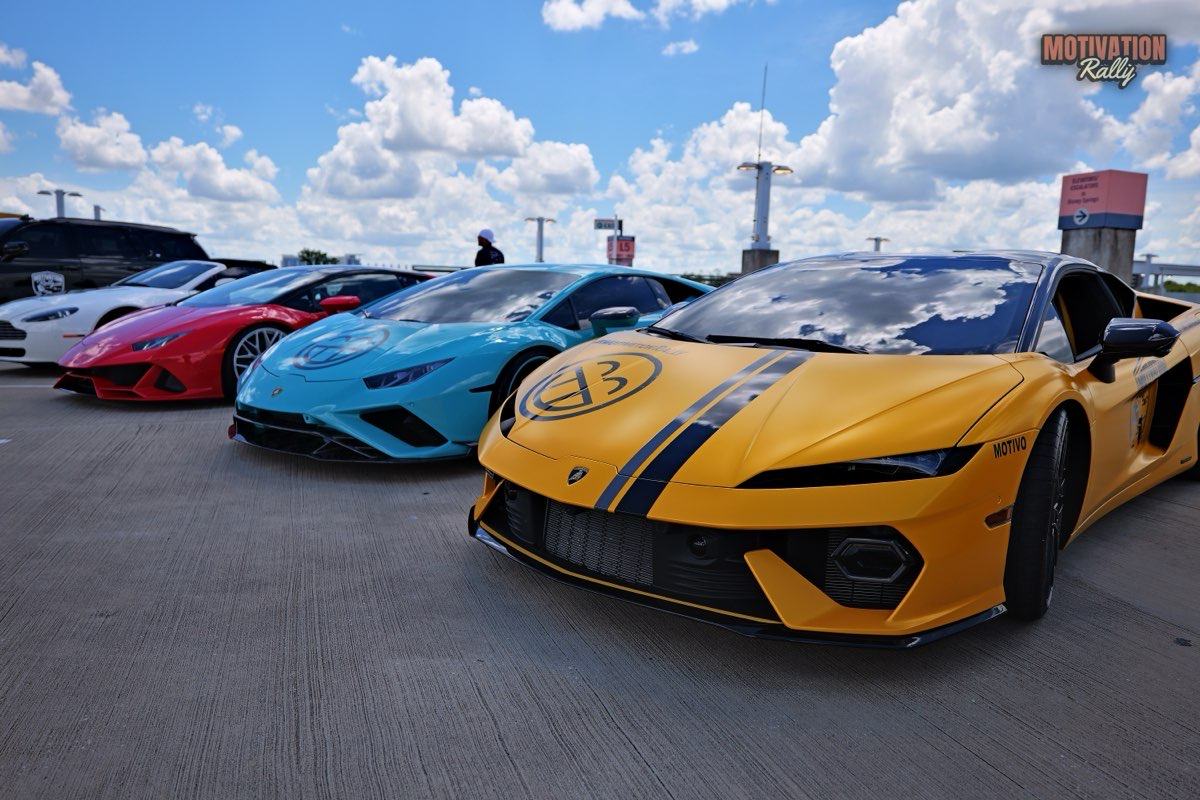 Four Lamborghinis parked in a row, a matte yellow one closest, then turquoise, red and white.