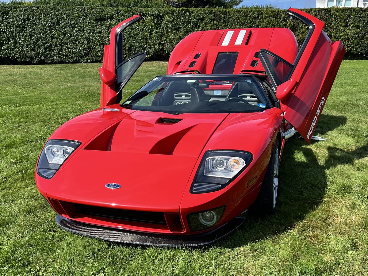 A red Ford GTX1 with both doors raised on the lawn at Rough Point