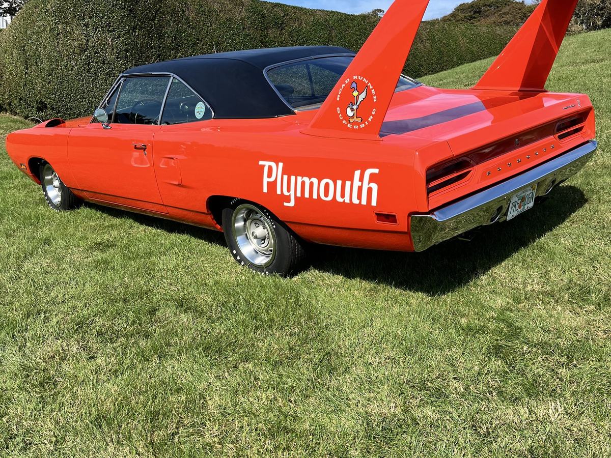 An orange 1970 Plymouth Superbird with a tall rear wing on the grass at Rough Point
